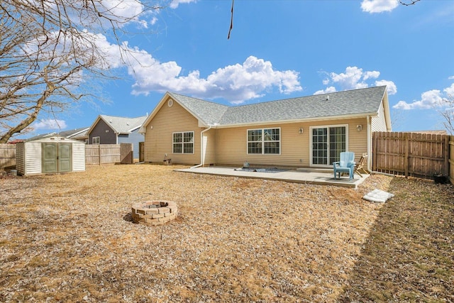 back of house featuring a fire pit, a storage unit, a patio area, and a fenced backyard