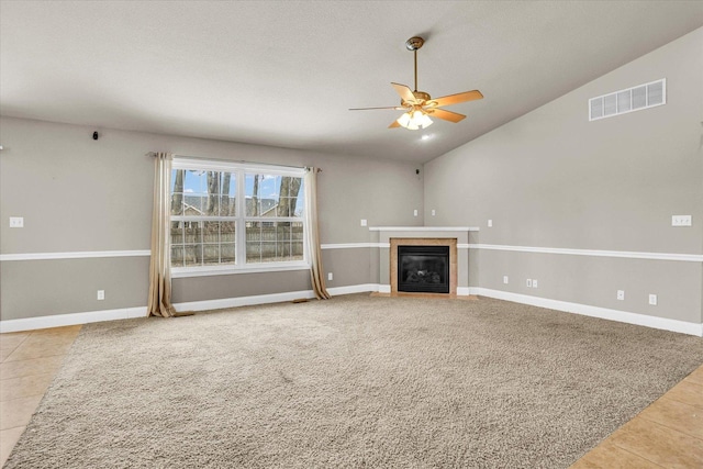 unfurnished living room featuring carpet, visible vents, a tiled fireplace, vaulted ceiling, and tile patterned floors