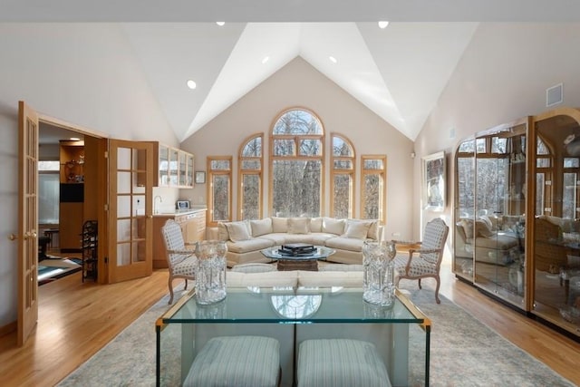 living room featuring french doors, high vaulted ceiling, and light hardwood / wood-style flooring