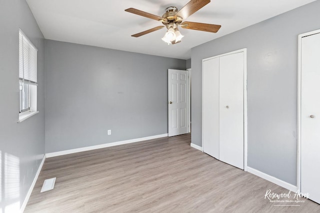 unfurnished bedroom featuring multiple closets, ceiling fan, and light wood-type flooring