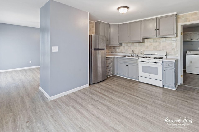 kitchen featuring stainless steel fridge, gray cabinets, washer / clothes dryer, and white range with gas stovetop