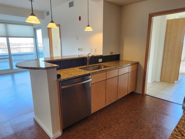 kitchen featuring pendant lighting, sink, dark stone counters, stainless steel dishwasher, and kitchen peninsula