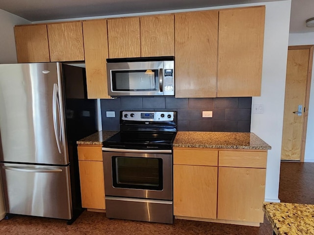 kitchen with light stone countertops, appliances with stainless steel finishes, and backsplash