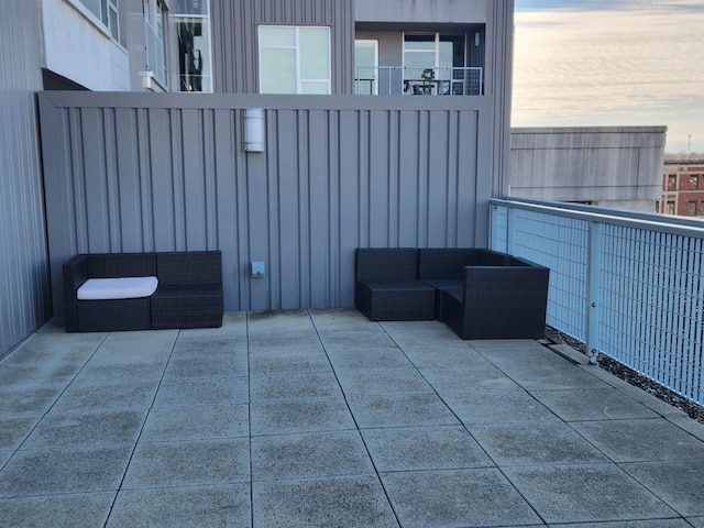 balcony at dusk featuring an outdoor living space and a patio area