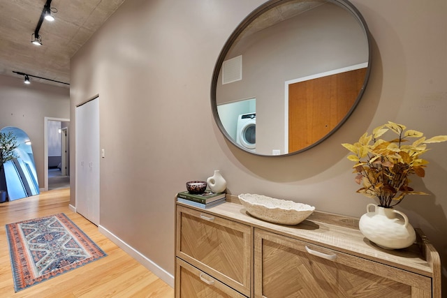 hall featuring washer / clothes dryer, track lighting, and light wood-type flooring