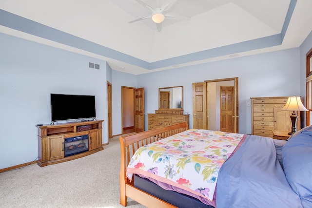 bedroom with a ceiling fan, visible vents, baseboards, a raised ceiling, and light colored carpet