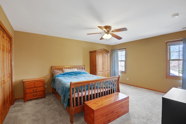 bedroom featuring baseboards, multiple windows, light colored carpet, and ceiling fan