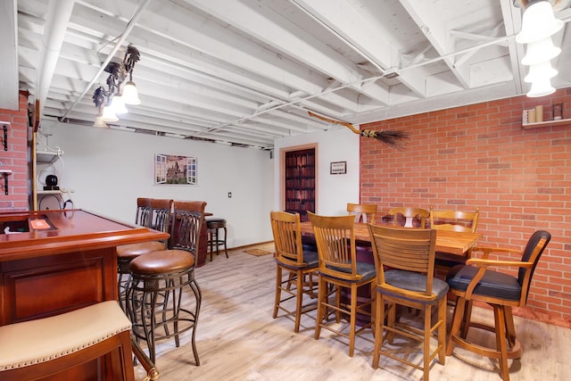 dining area featuring a dry bar, brick wall, and light wood-type flooring