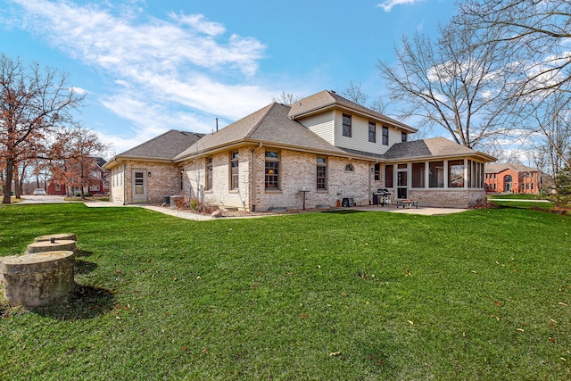 back of property with roof with shingles, a yard, a sunroom, a patio area, and brick siding