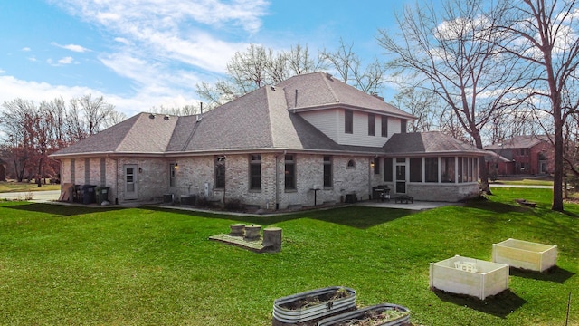 back of property featuring a patio, a sunroom, a yard, a shingled roof, and brick siding