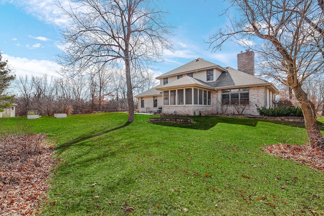 rear view of house with a shingled roof, a yard, a sunroom, and a chimney