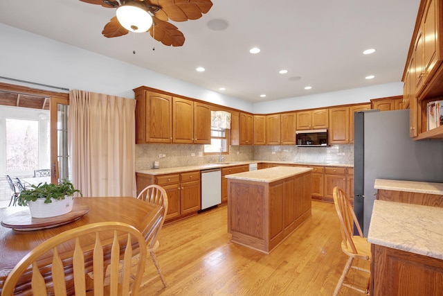 kitchen featuring a sink, a kitchen island, light wood-style floors, appliances with stainless steel finishes, and ceiling fan