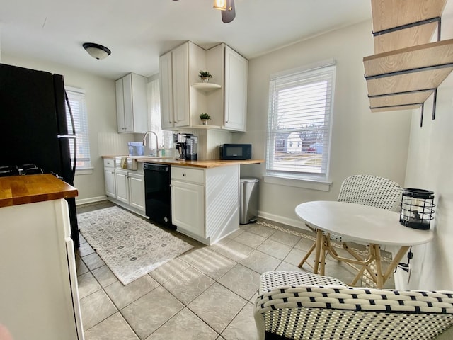 kitchen with butcher block counters, white cabinetry, black appliances, and light tile patterned flooring