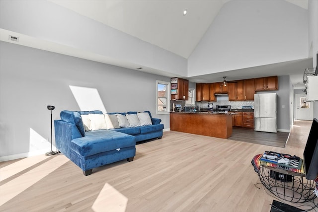 living room featuring high vaulted ceiling and light wood-type flooring