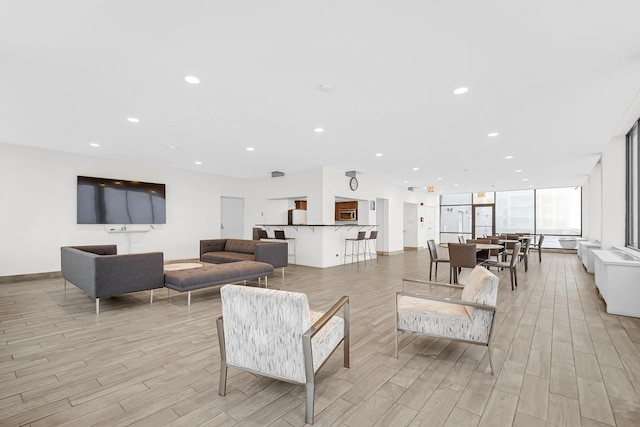 living area with recessed lighting, light wood-style flooring, and baseboards