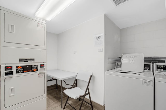 community laundry room featuring baseboards, visible vents, light wood-style flooring, and stacked washing maching and dryer