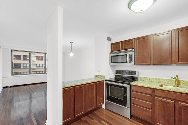 kitchen featuring visible vents, dark wood-style floors, light stone counters, stainless steel appliances, and a sink