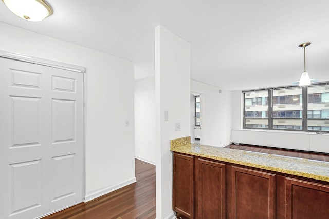 kitchen featuring dark wood-style floors, pendant lighting, baseboards, and light stone countertops