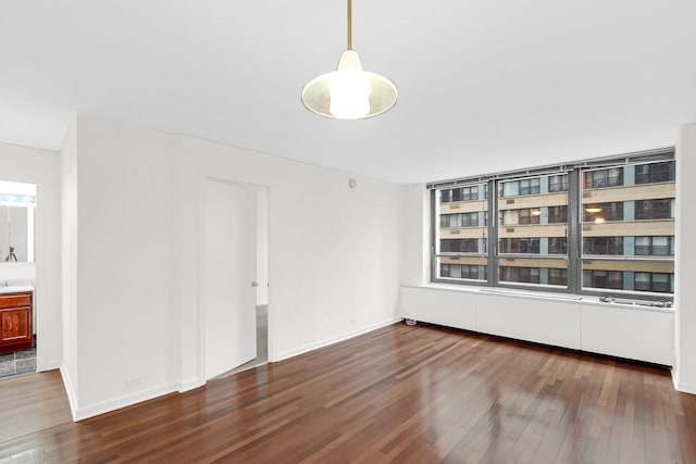 spare room with baseboards and wood finished floors