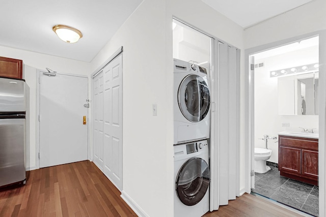 laundry area featuring laundry area, visible vents, dark wood-style flooring, and stacked washer and clothes dryer