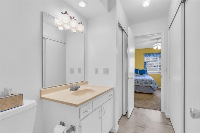 bathroom with vanity, ceiling fan, a textured ceiling, and toilet