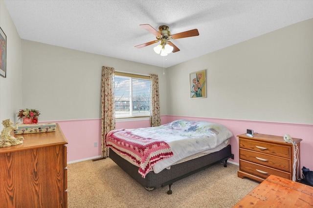 bedroom featuring ceiling fan, light carpet, and a textured ceiling