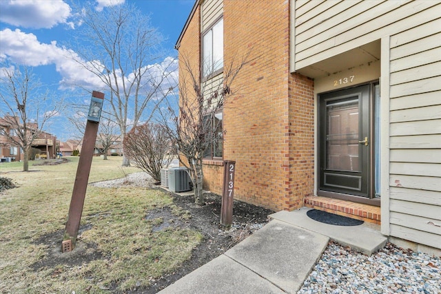 entrance to property with a yard and central air condition unit