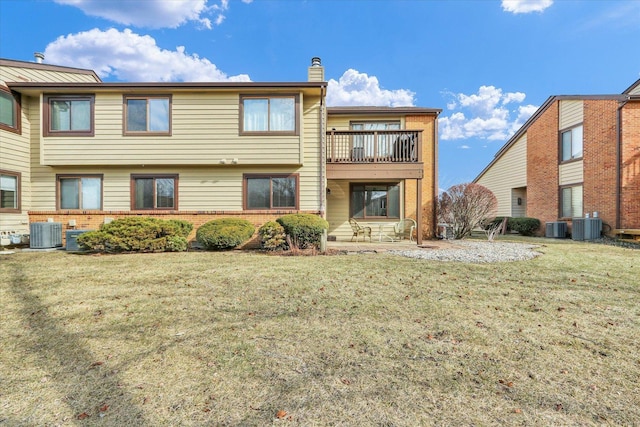 back of property featuring a balcony, a lawn, and central air condition unit