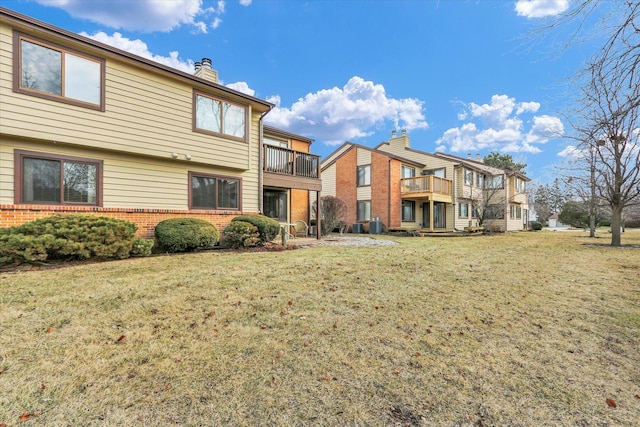 back of property featuring a balcony and a lawn