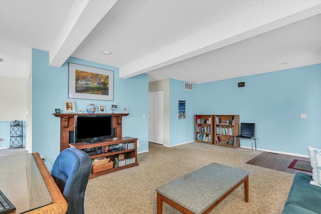 living room featuring a textured ceiling, beamed ceiling, and carpet