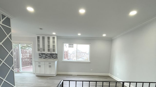 kitchen featuring tasteful backsplash, crown molding, white cabinets, and light hardwood / wood-style flooring