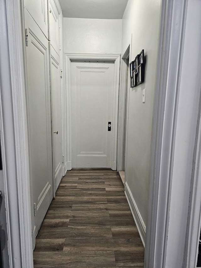 hallway featuring baseboards and dark wood finished floors