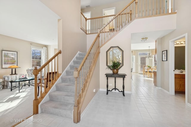 stairs featuring tile patterned flooring, a high ceiling, and baseboards