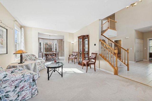 tiled living area with a notable chandelier, stairway, carpet flooring, and baseboards