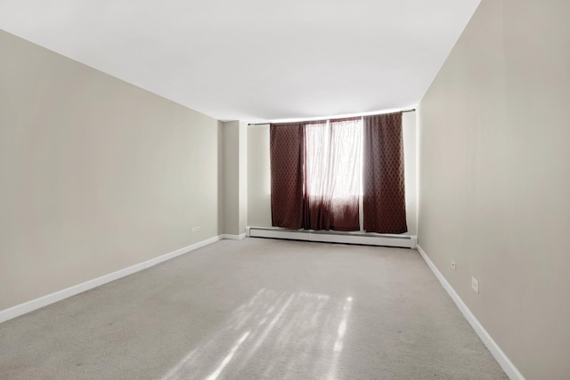 spare room with a baseboard heating unit and light colored carpet