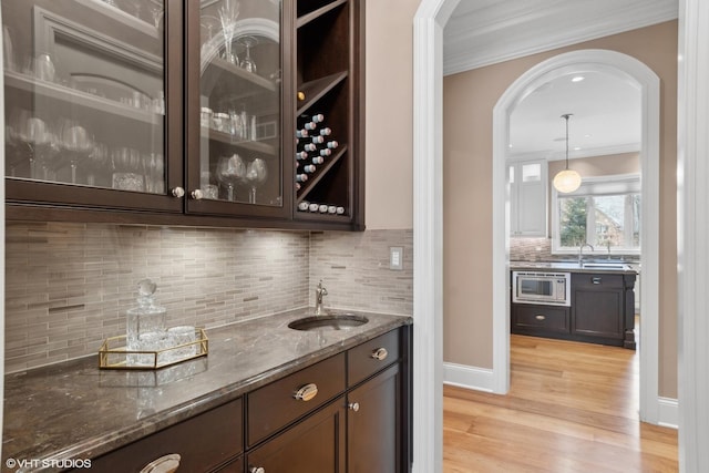 6 Ivy Ln, Oak Brook, IL 60523 - bar featuring ornamental molding, light wood-style flooring, arched walkways, a sink, and wet bar