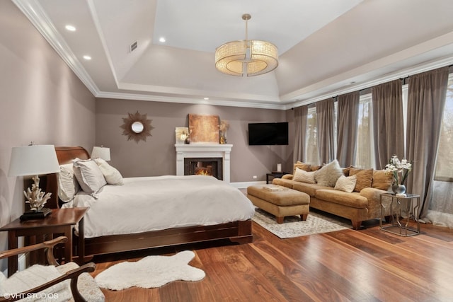 6 Ivy Ln, Oak Brook, IL 60523 - bedroom with a lit fireplace, visible vents, wood finished floors, a raised ceiling, and recessed lighting