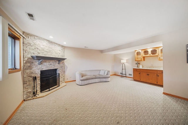 unfurnished living room featuring light colored carpet, a fireplace, and sink