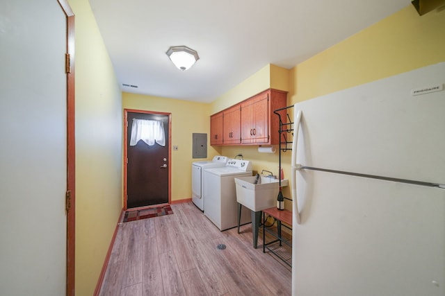 clothes washing area with sink, electric panel, independent washer and dryer, cabinets, and light wood-type flooring