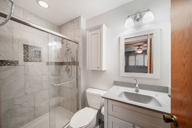 bathroom featuring walk in shower, ceiling fan, vanity, and toilet