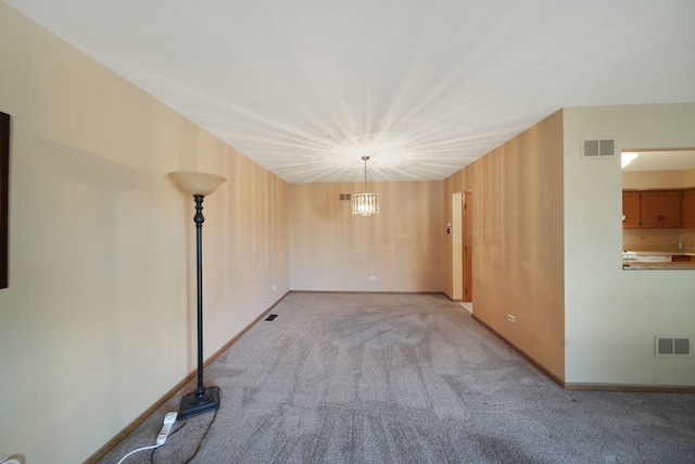 carpeted empty room with a notable chandelier