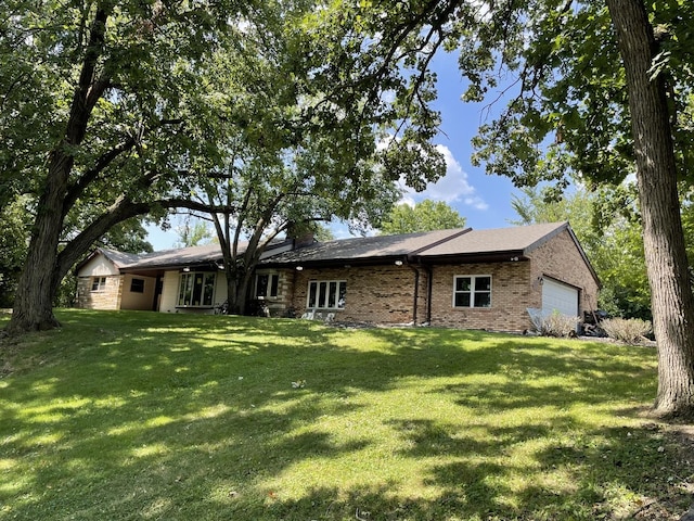 rear view of house with brick siding, a lawn, and a garage