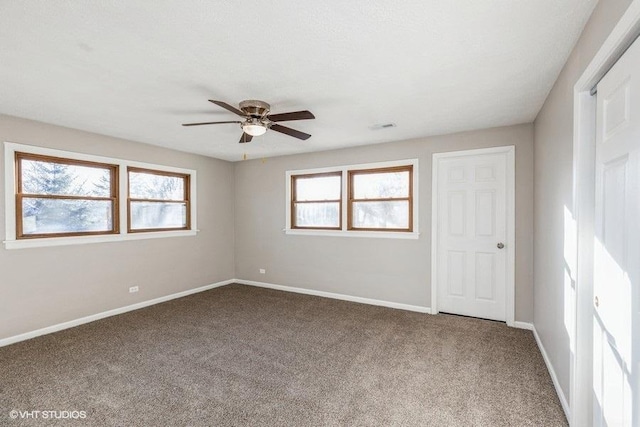 empty room with baseboards, carpet floors, visible vents, and ceiling fan