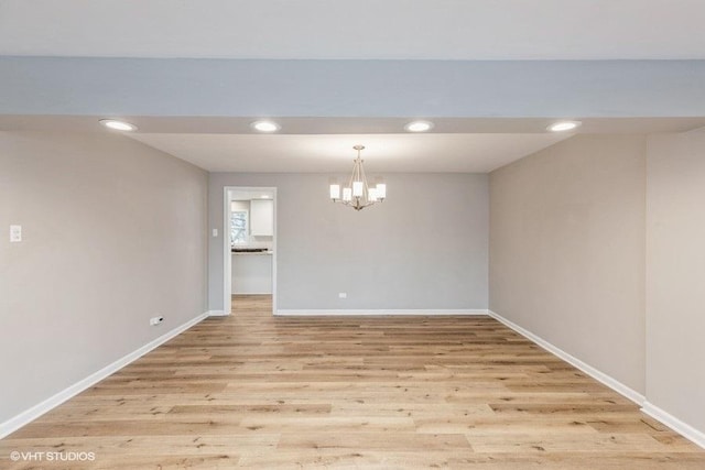 unfurnished dining area featuring an inviting chandelier and light wood-type flooring