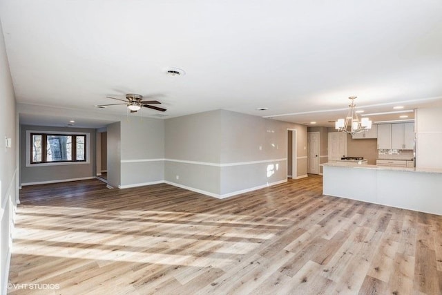 unfurnished living room featuring ceiling fan with notable chandelier, visible vents, light wood-style floors, and baseboards