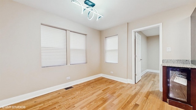 spare room with wine cooler and light wood-type flooring