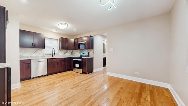 kitchen with sink, dark brown cabinets, stainless steel appliances, tasteful backsplash, and light hardwood / wood-style floors
