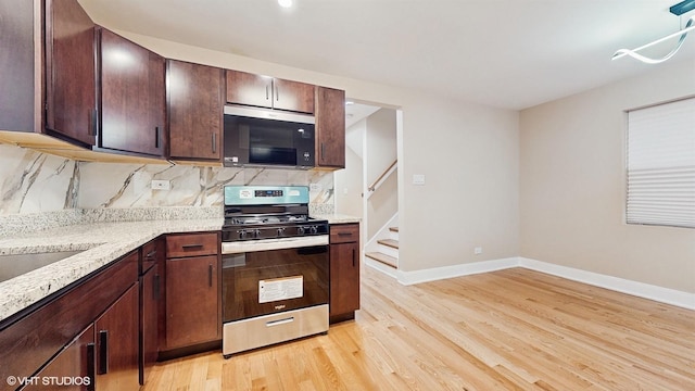 kitchen with appliances with stainless steel finishes, backsplash, dark brown cabinetry, light stone counters, and light hardwood / wood-style flooring