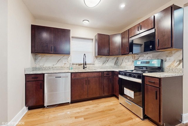kitchen with appliances with stainless steel finishes, sink, dark brown cabinetry, light hardwood / wood-style floors, and light stone countertops