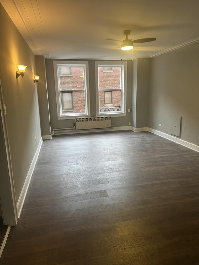 spare room featuring dark wood-style flooring, baseboards, ceiling fan, and radiator heating unit